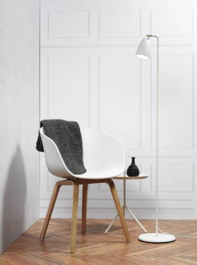 floor lamp next next to a chair with blanket draped